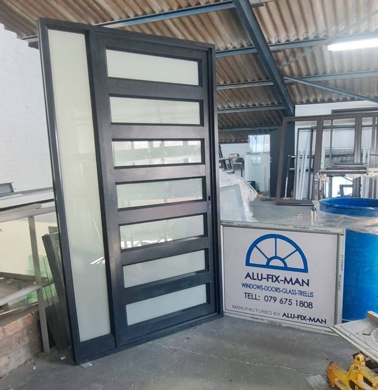 A black aluminium door with frosted glass panels in the workshop