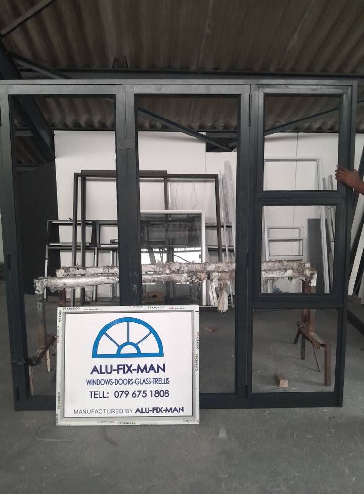 A black aluminium folding door set in the workshop, beside the signboard
