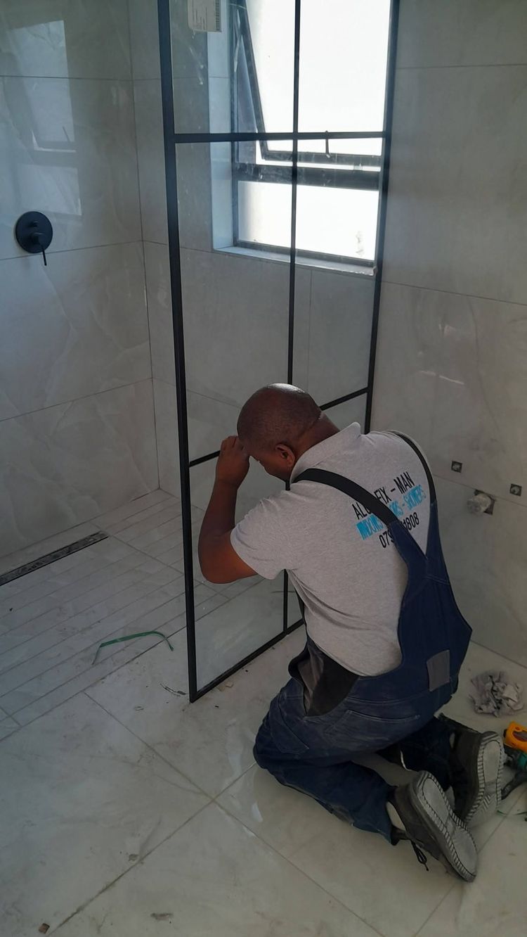 An installer fitting a black grid-style shower screen