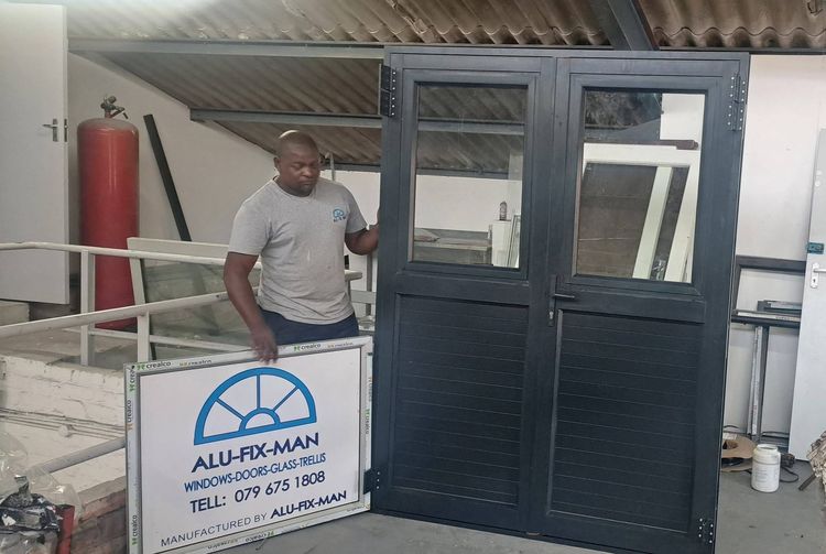 An installer with black aluminium double doors, glass above and panels below, in the workshop