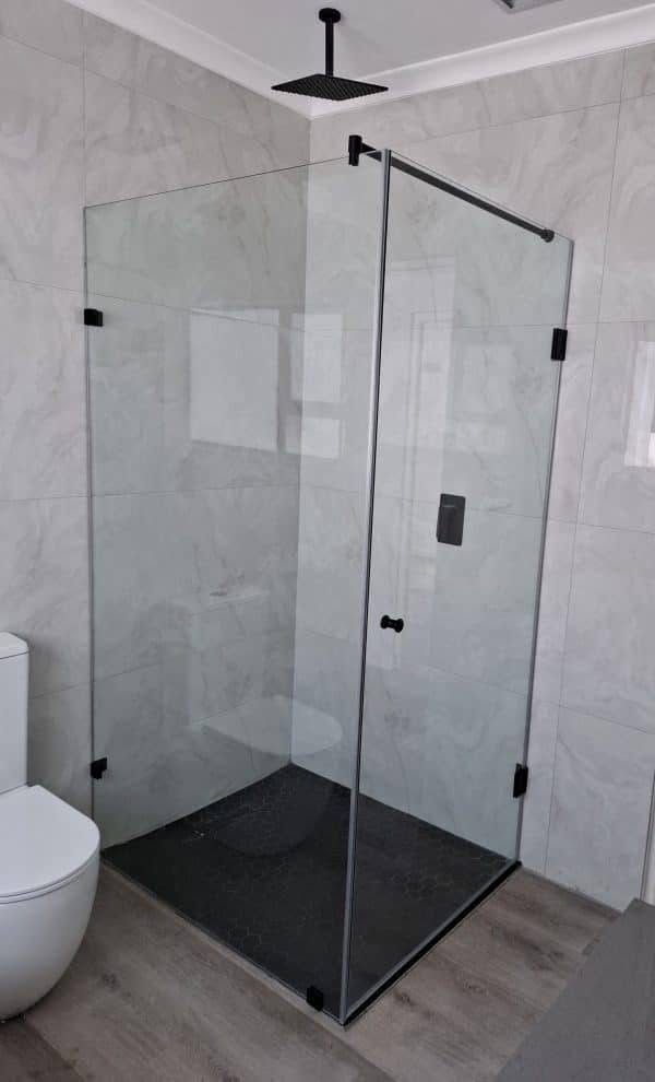 A frameless glass corner shower with black fittings