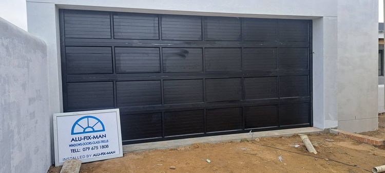 A black aluminium garage door with the Alu-Fix-Man signboard