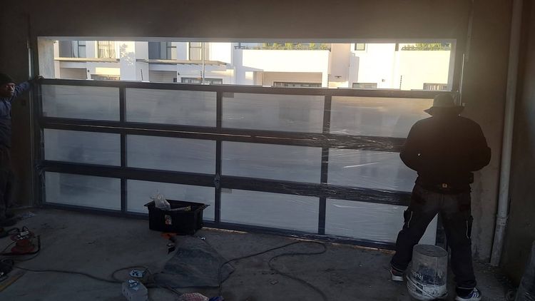 An installer fitting a glazed aluminium garage door
