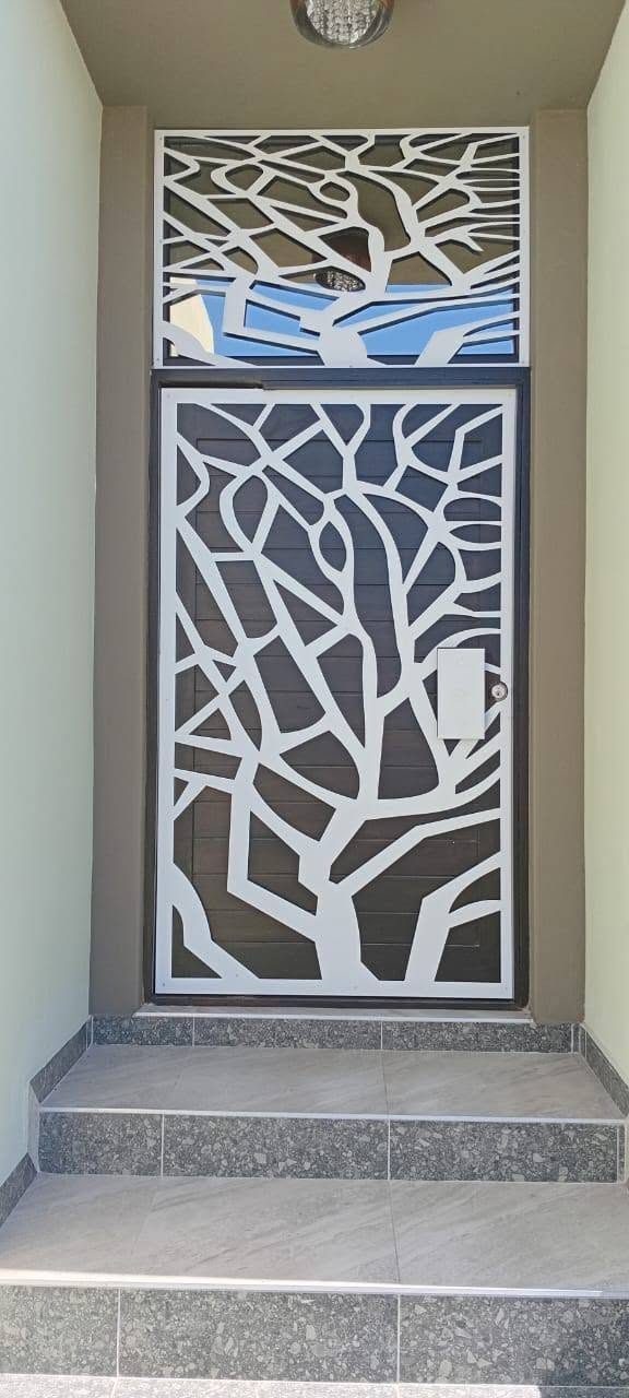 A white door panel with a laser-cut tree pattern at the top of some steps