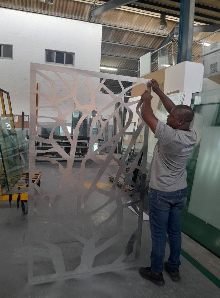 An installer lifting a laser-cut aluminium screen in the workshop
