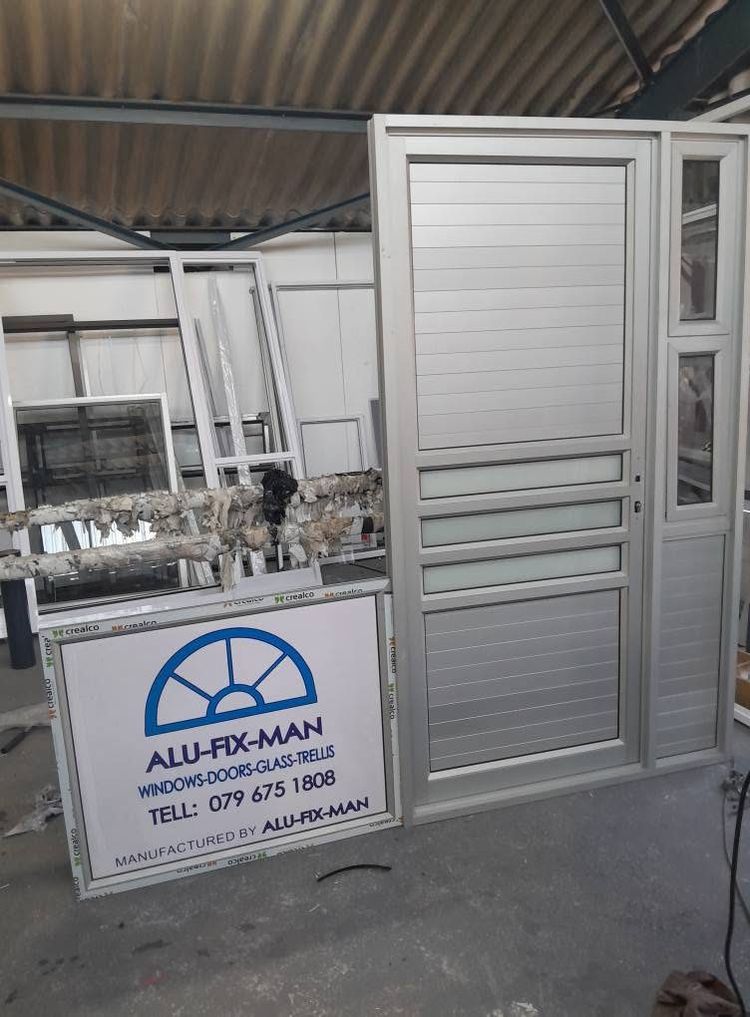 A silver aluminium door with louvre panels and a side light, in the workshop