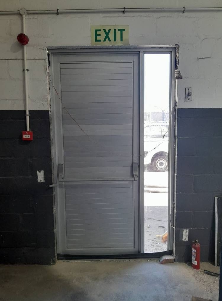 A silver aluminium louvre door under an exit sign