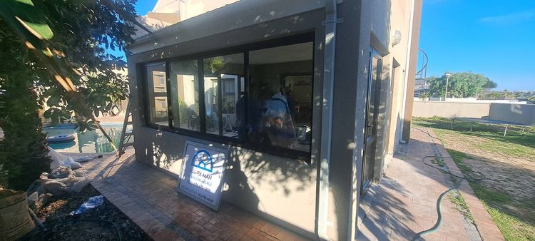 A row of black aluminium windows on an office, with the signboard