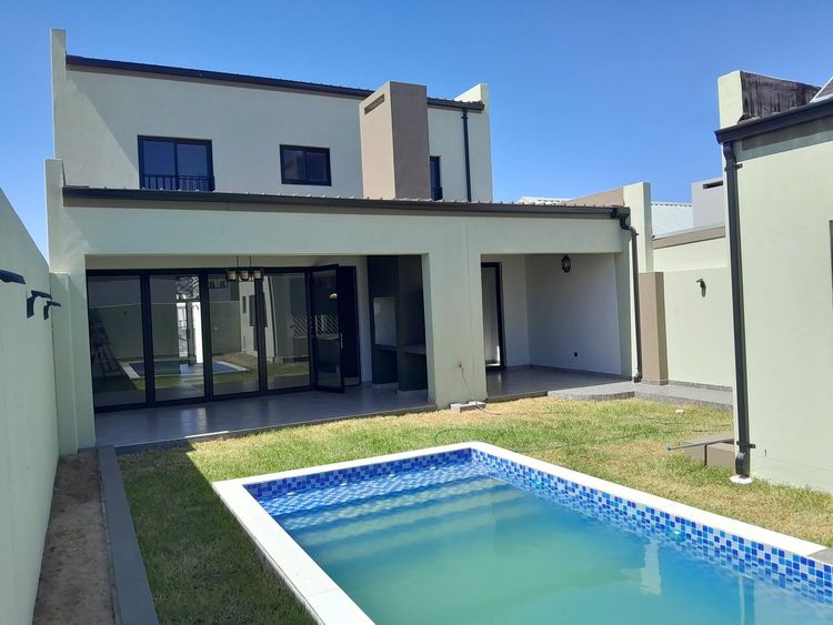 Black aluminium stacking doors and windows on a double-storey house with a mosaic pool