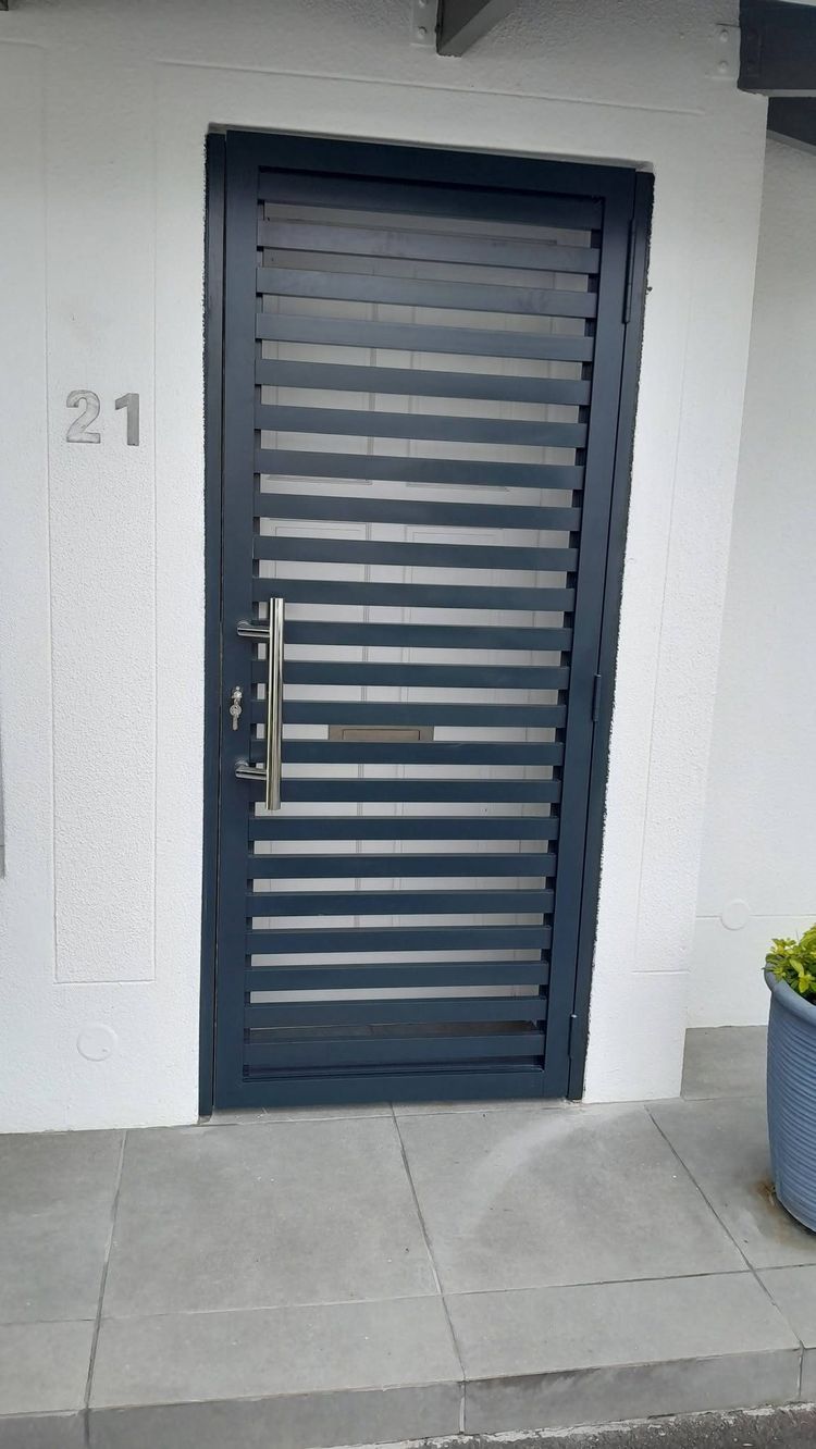 A charcoal slatted aluminium security door at a front entrance