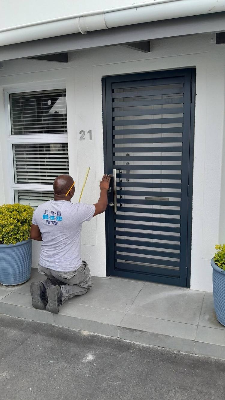 An Alufixman installer fitting a charcoal slatted door