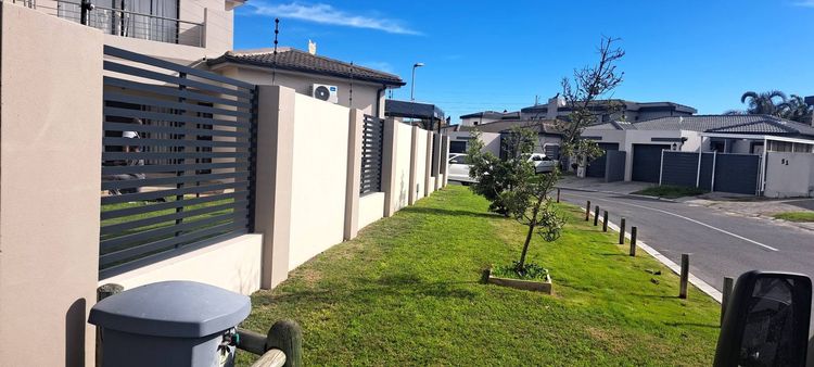 Aluminium slat fence panels on a garden wall along a street