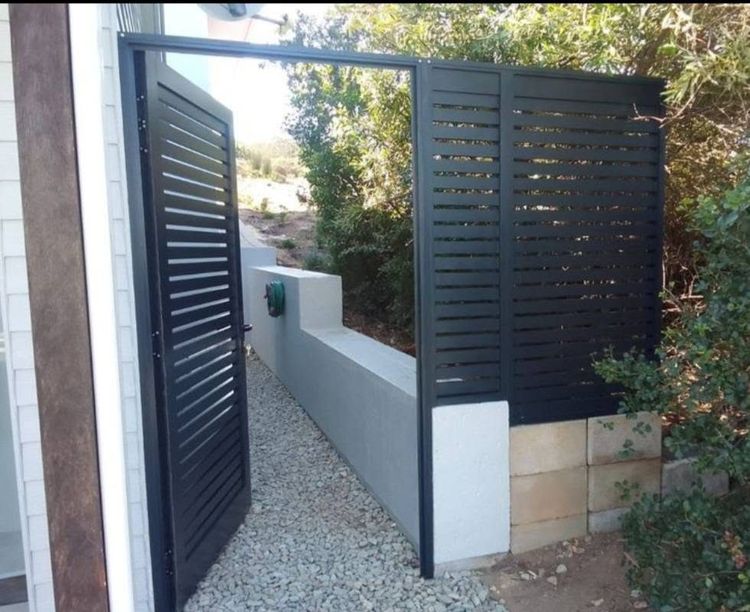 A slatted aluminium gate and matching panel on a side yard