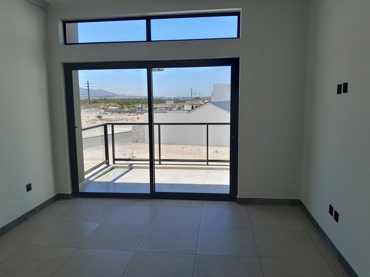A black aluminium sliding door opening onto a balcony