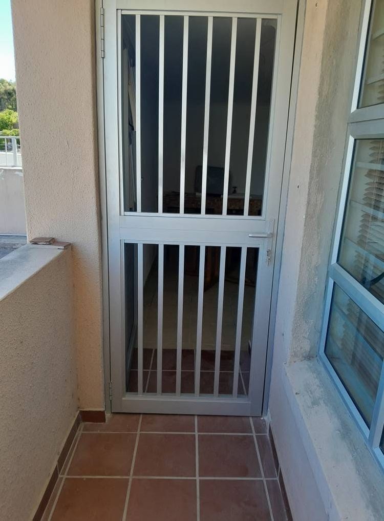A white aluminium trellis security gate on a balcony