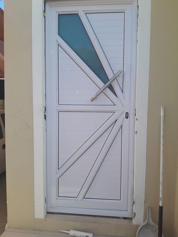 A white aluminium door with diagonal bars and a small glass inset