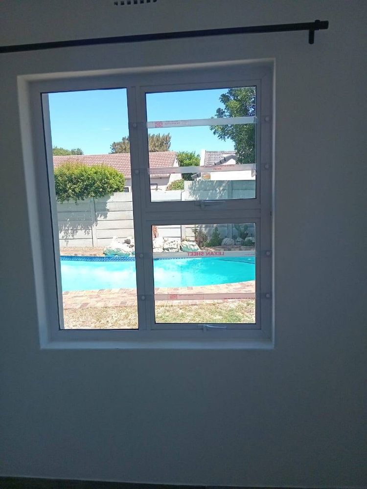 A new white aluminium window looking out over a garden pool